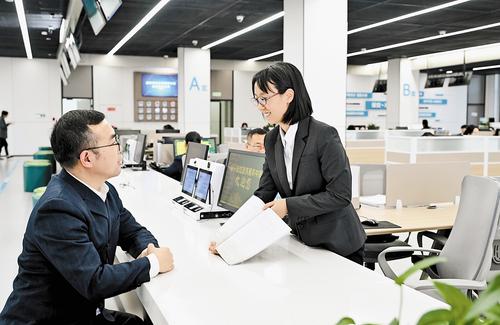 11月14日，雄安新區政務服務中心投資建設項目服務區綜合受理窗口，雄安新區建設和交通管理局工作人員張雅然（右）為辦事群眾解疑答惑。 本報記者 劉光昱攝