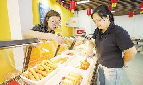 7月11日，位于雄安·老字號(hào)商業(yè)街的中華老字號(hào)天津“迎賓”牌肉制品門店內(nèi)，顧客正在挑選火腿。本報(bào)見習(xí)記者 李暢攝